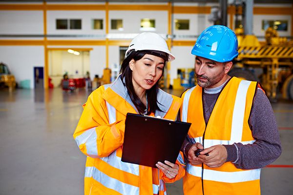 Two warehouse workers wearing safety gear having a discussion