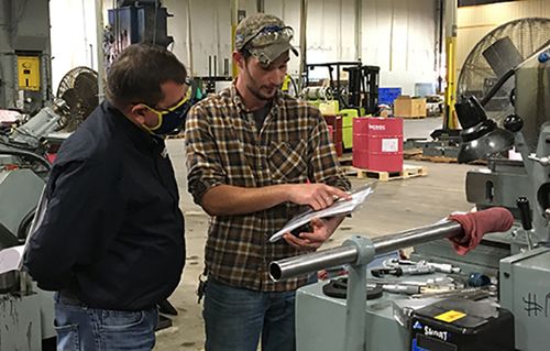 Machine worker reviews document with a man in an industrial environment
