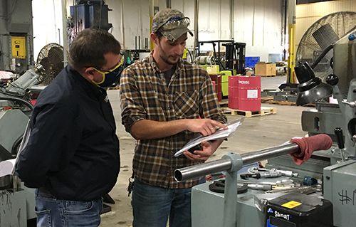 Machine worker reviews a document with a WVU Industrial Extension employee.